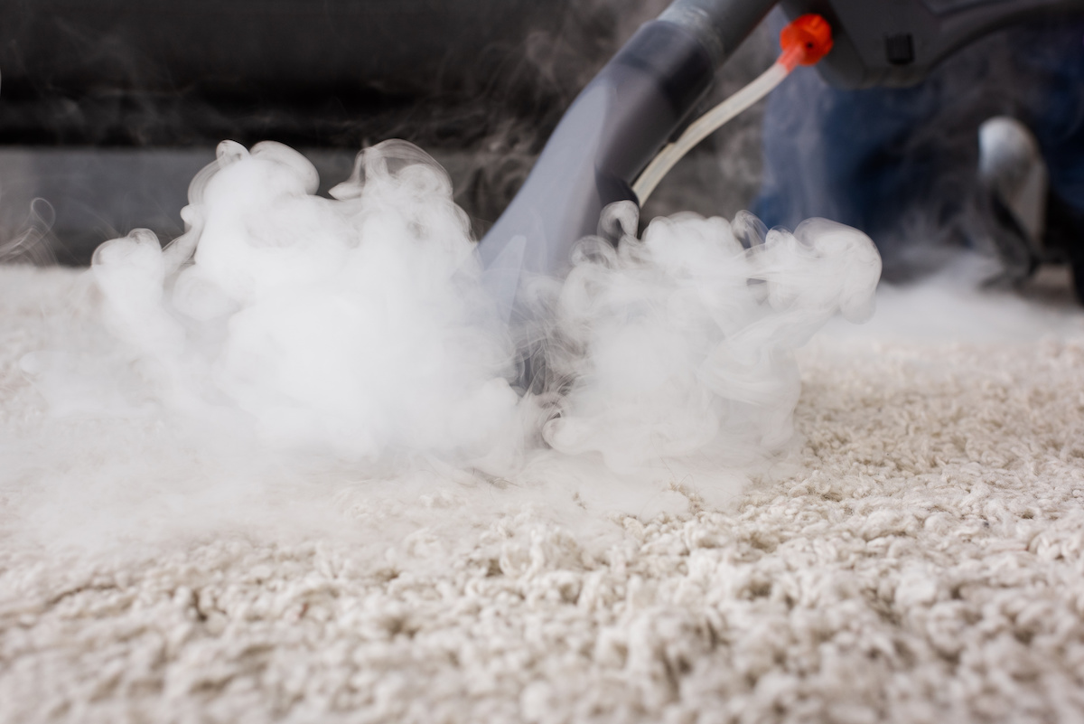 Selective focus of vacuum cleaner with hot steam on carpet at home