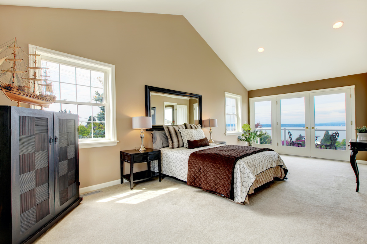 Beige classic large bedroom with water view and carpet.